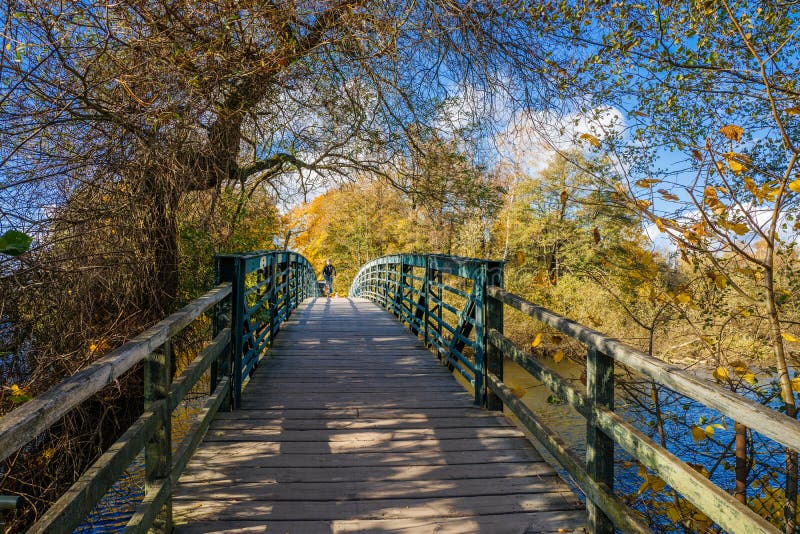 Norrkoping, Sweden - October 25, 2015: Biker crossing a bridge on a sunny and colorful autumn day at Motala Stream in Norrkoping. Norrkoping, Sweden - October 25, 2015: Biker crossing a bridge on a sunny and colorful autumn day at Motala Stream in Norrkoping.