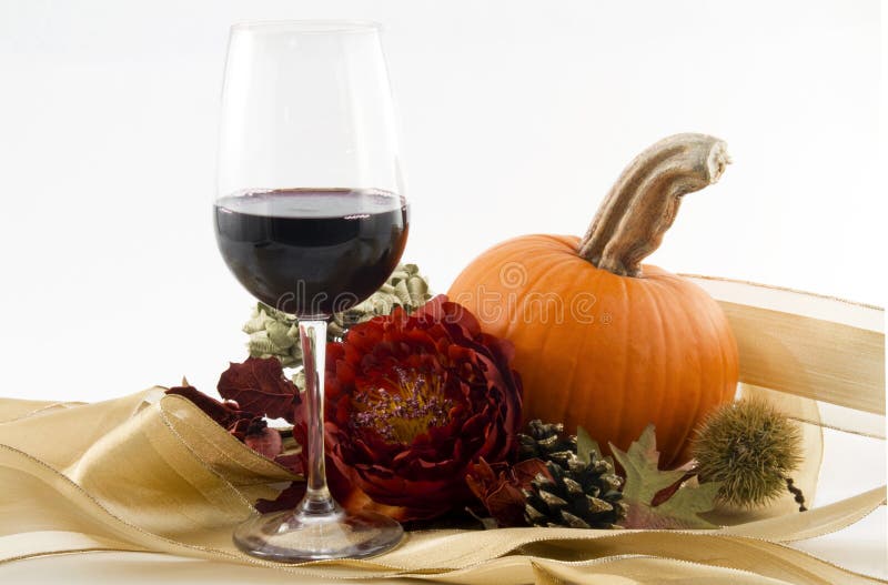 Un bicchiere di vino rosso con rosso, fioritura, stagione di zucca arancione e radica di castagno, pino, cono e foglie secche, offrono un elegante brindisi e festa d'autunno.