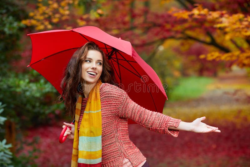 Autumn woman in autumn park with red umbrella, scarf and leather