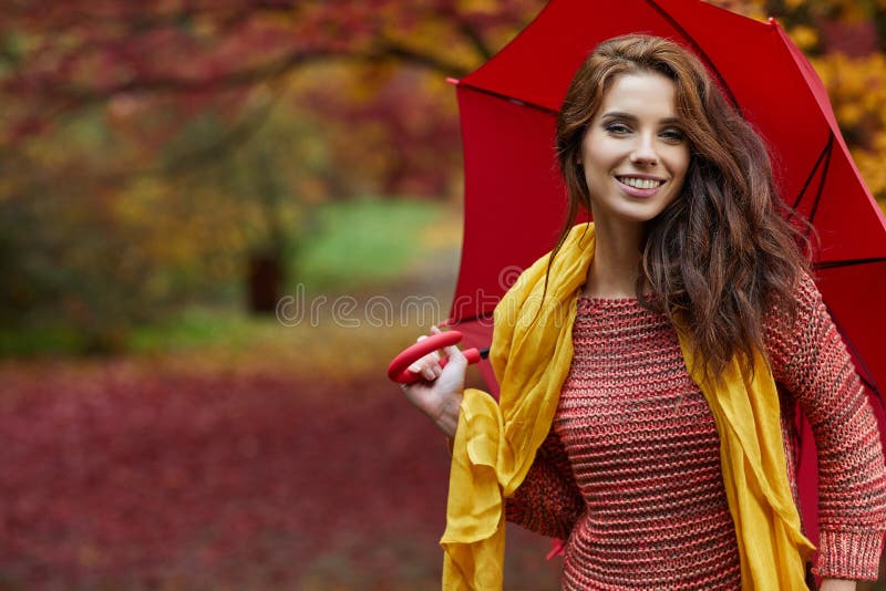 Autumn woman in autumn park with red umbrella, scarf and leather