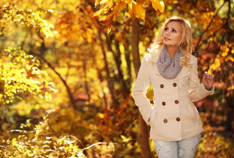 Autumn Woman. Fall. Blonde Beautiful Girl with Yellow Leaves