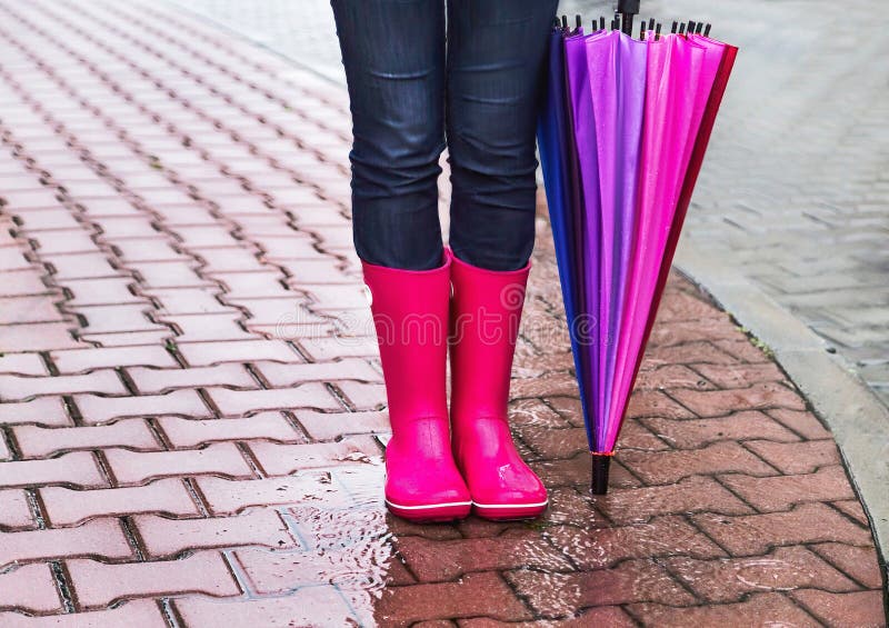 Autunno Protezione nella pioggia La donna (ragazza) che porta gli stivali di gomma rosa ed ha ombrello variopinto fotografie stock libere da diritti Autunno Protezione nella pioggia La donna (ragazza) che porta gli stivali di gomma rosa ed ha ombrello variopinto fotografie stock libere da diritti