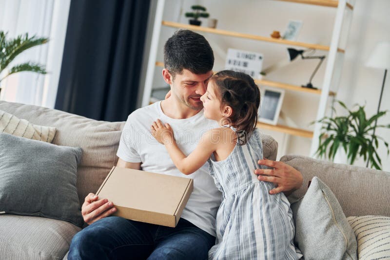 Avec boîte cadeau. le père en civil est à la maison avec sa fille photos stock