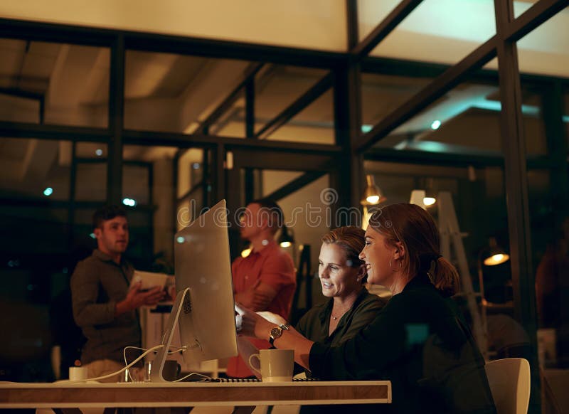 Avec quelques heures supplémentaires bien faire autant. deux femmes d'affaires qui regardent quelque chose sur un ordinateur dans image stock