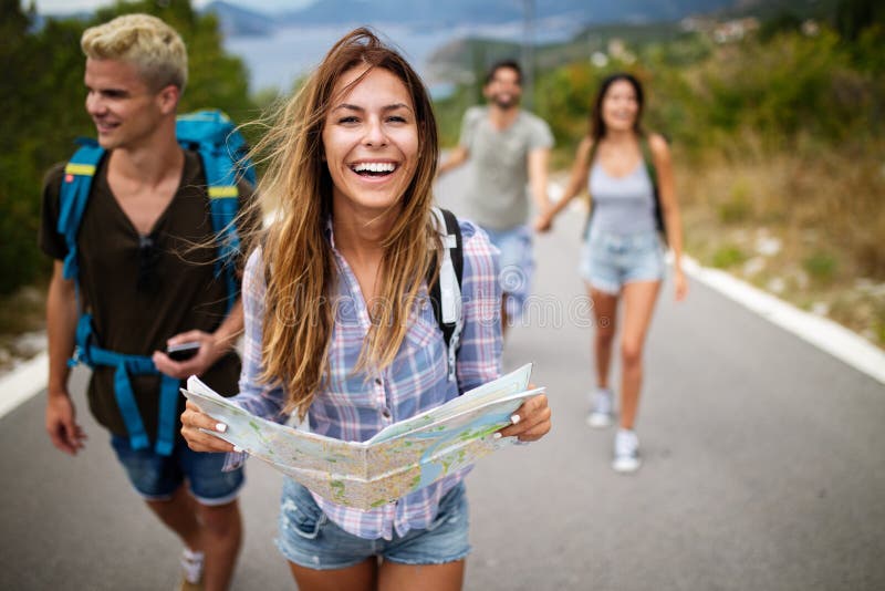 Aventura, curso, turismo e conceito dos povos - grupo de amigos de sorriso com trouxas e mapa