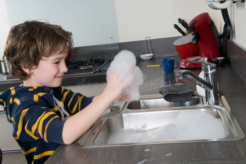 Boy having fun with soap while doing the dishes. Boy having fun with soap while doing the dishes