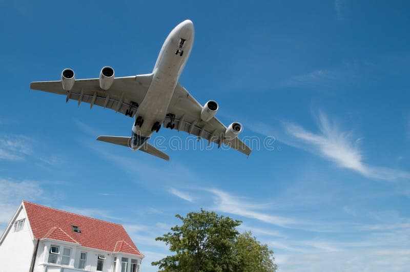 Large jet aircraft on landing approach over suburban housing. Large jet aircraft on landing approach over suburban housing