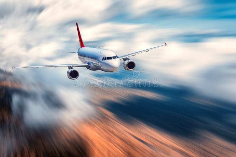 Airplane with motion blur effect. Landscape with flying passenger airplane and blurred background with sky with low clouds, orange forest at sunset. Passenger airplane is landing. Commercial aircraft. Airplane with motion blur effect. Landscape with flying passenger airplane and blurred background with sky with low clouds, orange forest at sunset. Passenger airplane is landing. Commercial aircraft