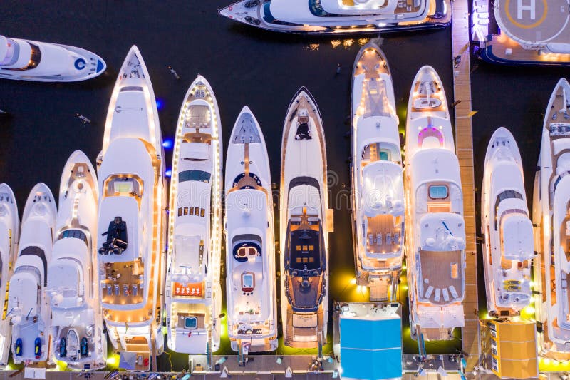 Avión directo sobre la pista de los lujosos Super yates iluminados por la noche en un espectáculo de barcos internacionales en Fo imagenes de archivo