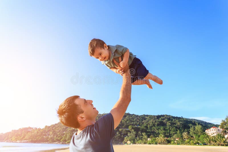 Avla att spela med hans son på stranden på solnedgångtiden royaltyfri fotografi Avla att spela med hans son på stranden på solnedgångtiden royaltyfri fotografi