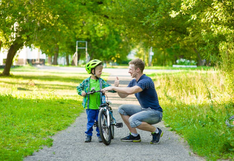 Avla samtal med hans son som rider en cykel royaltyfri foto Avla samtal med hans son som rider en cykel royaltyfri foto