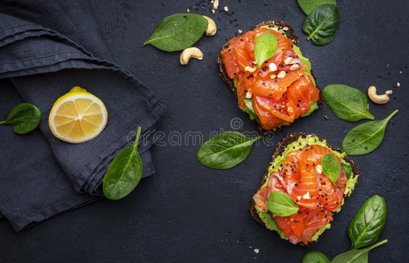 Sandviș cu avocado și somon sau pâine prăjită pe pâine de secară cu nuci de cajou zdrobite de spanac și semințe de susan și fond n royalty free stock photo
