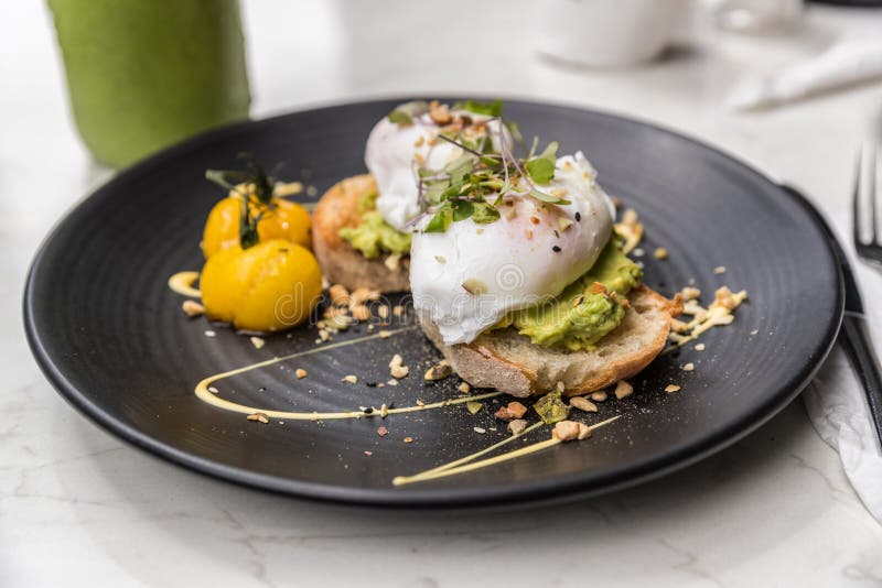 Avocado toast with eggs breakfast plate at restaurant closeup. Trendy healthy morning food at cafe with guacamole and poached egg stock photo Avocado toast with eggs breakfast plate at restaurant closeup. Trendy healthy morning food at cafe with guacamole and poached egg stock photo