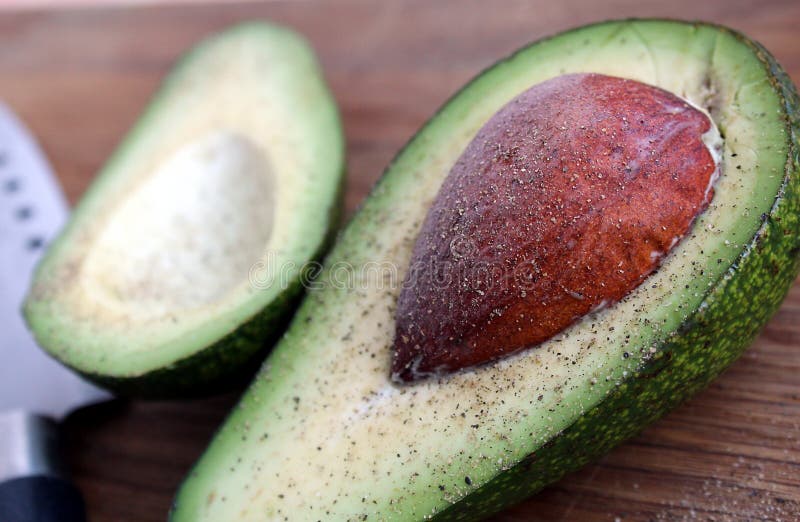 Avocado verde con l'osso che si trova su un tagliere immagini stock