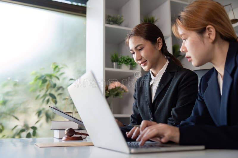 Avocat et client travaillant ensemble sur des documents juridiques et un ordinateur portable dans un bureau lumineux. image stock