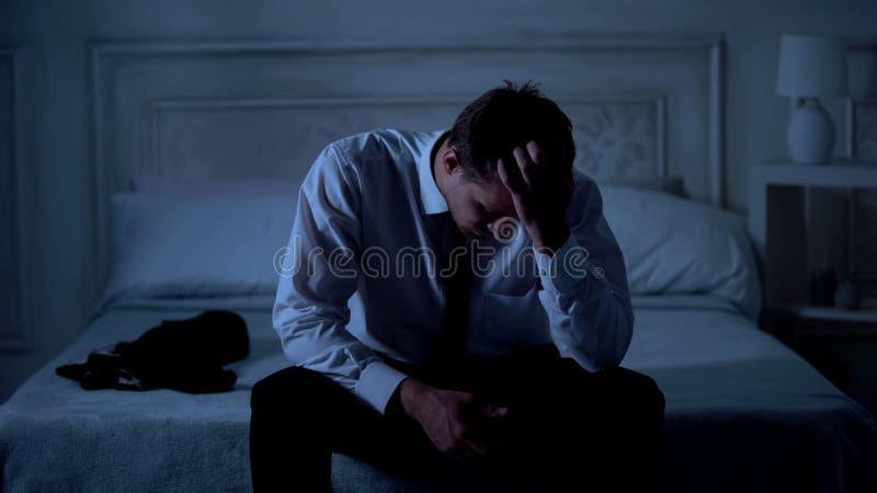 Sad lawyer sitting on bed at night, failed case, disappointment and frustration, stock photo. Sad lawyer sitting on bed at night, failed case, disappointment and frustration, stock photo