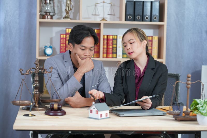 Avocatul care îl consiliază pe client cu privire la acordul ipotecar la domiciliu în timpul negocierilor cu un model de casă și cu royalty free stock images