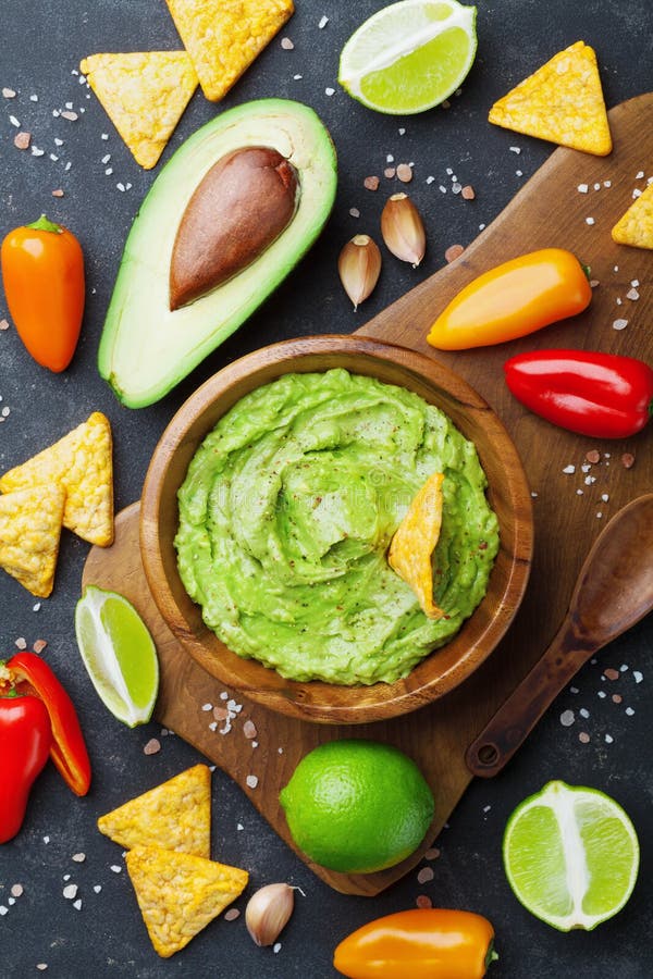 Avocado guacamole with ingredients pepper, lime and nachos on table top view. Traditional mexican food. Avocado guacamole with ingredients pepper, lime and nachos on table top view. Traditional mexican food.