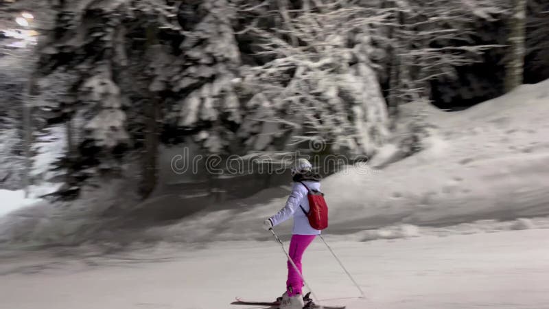 Avondskiën op de lichthelling met sneeuwbedekte bomen met vorst