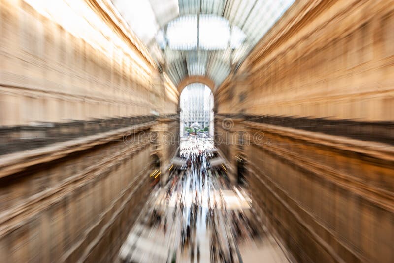 Intentionally motion blurred creative image of people and commuters walking in crowded Galleria Vittorio Emanuele II in Milan, Italy. Concept of Milan as fast-paced, busy city, movement, future. Intentionally motion blurred creative image of people and commuters walking in crowded Galleria Vittorio Emanuele II in Milan, Italy. Concept of Milan as fast-paced, busy city, movement, future.