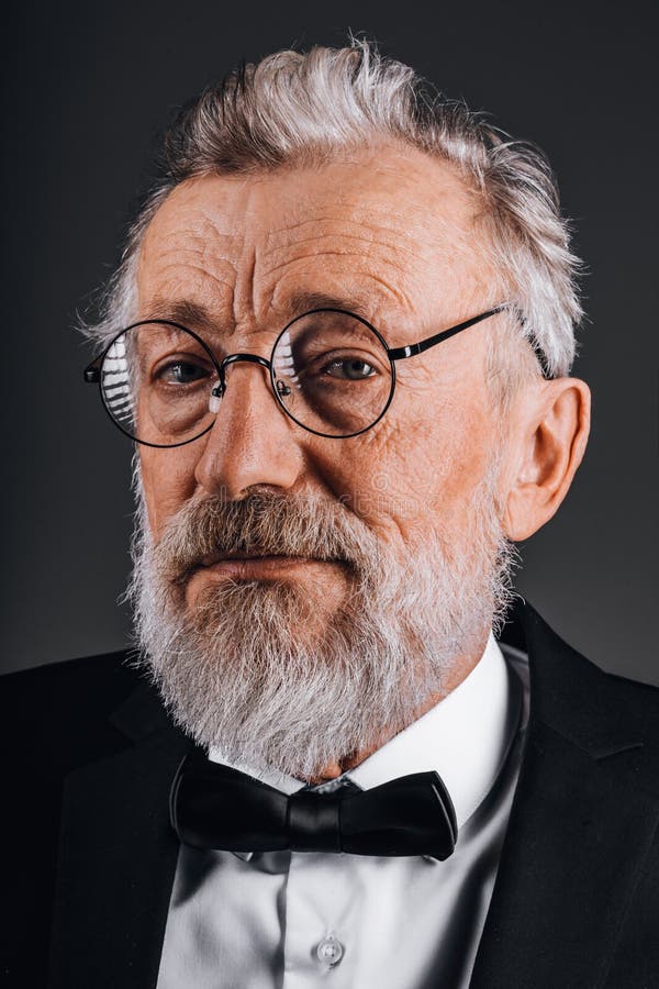 Avskärma porträtt av självsäker mogen man i tuxedo isolerad på svart bakgrund royaltyfri bild