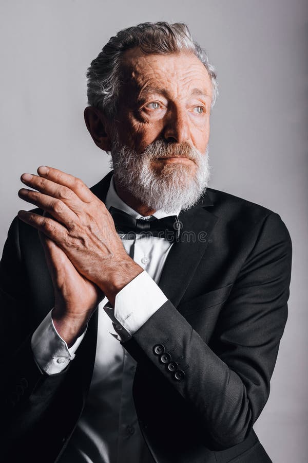 Avskärma porträtt av självsäker mogen man i tuxedo isolerad på svart bakgrund royaltyfria bilder