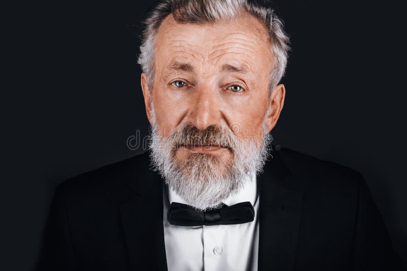 Avskärma porträtt av självsäker mogen man i tuxedo isolerad på svart bakgrund royaltyfri fotografi