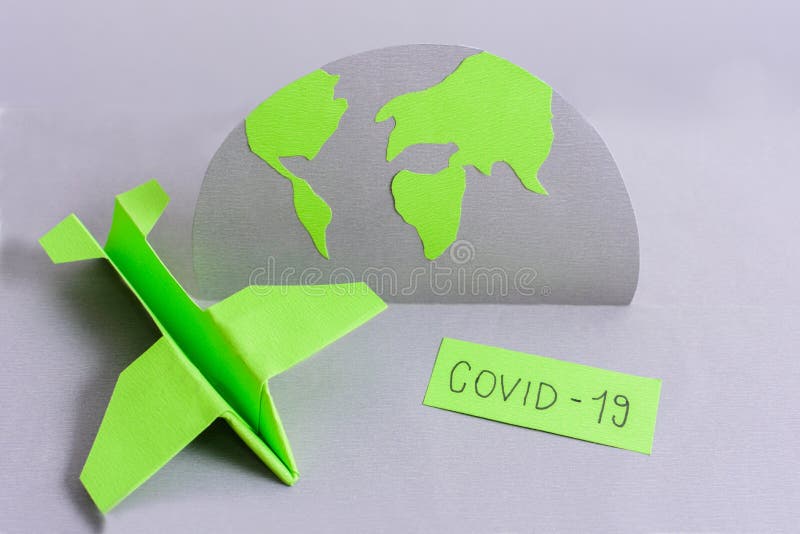 Avskärmning av grönt origami-plan bredvid en dekorativ pappersglob och covid19-tecken royaltyfria bilder