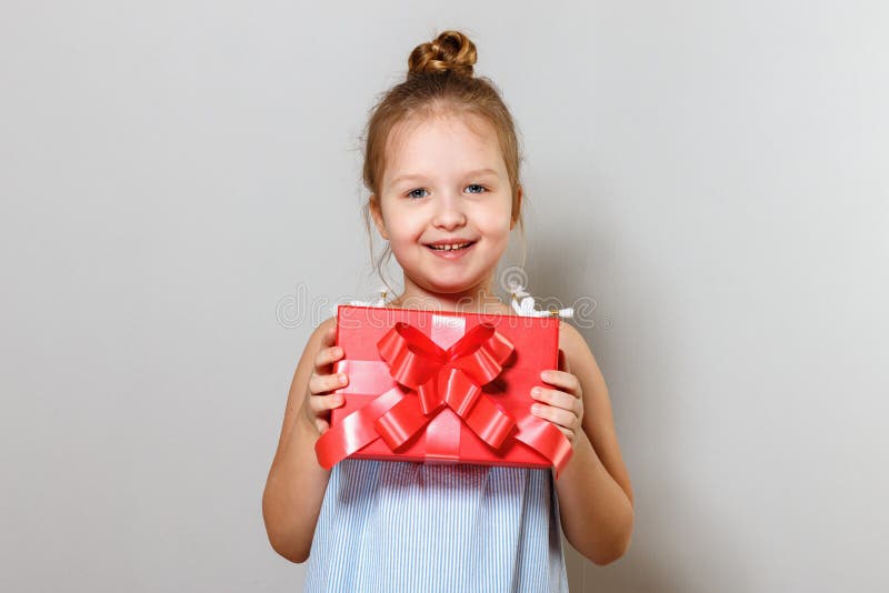 Avsluta porträtt av en söt liten flicka med en presentlåda Baby på grå bakgrund royaltyfri foto Avsluta porträtt av en söt liten flicka med en presentlåda Baby på grå bakgrund royaltyfri foto