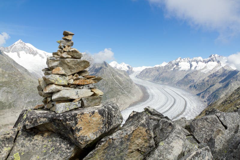 Concept for hiking, climbing, walkig and outdoor adventures: mountain top with rock cairn marking above Aletsch glacier Switzerland. Concept for hiking, climbing, walkig and outdoor adventures: mountain top with rock cairn marking above Aletsch glacier Switzerland