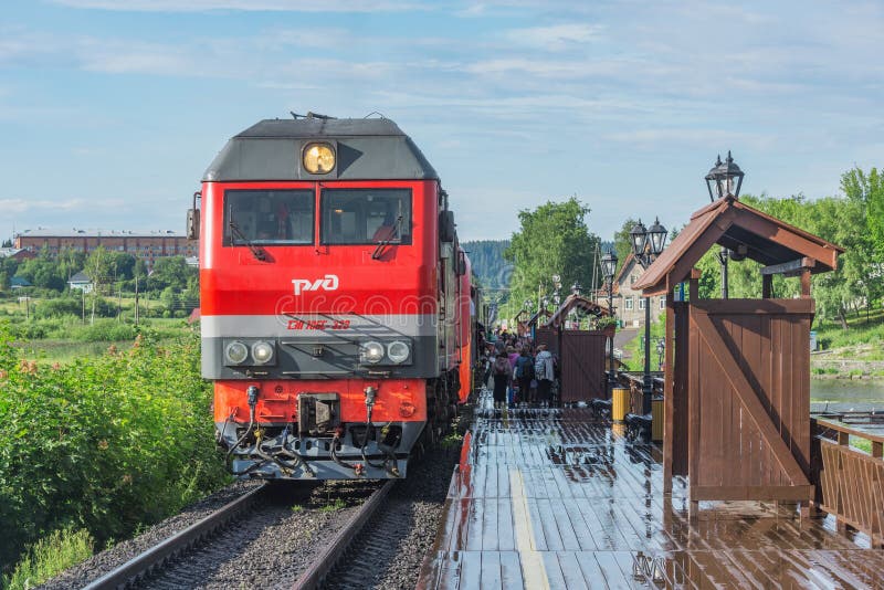 Avvicinamenti del treno passeggeri alla piattaforma di legno fotografia stock