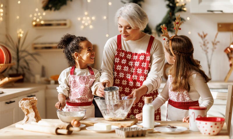 Avó de família multiétnica e dois filhos cozinhando biscoitos de natal juntos na cozinha foto de stock royalty free