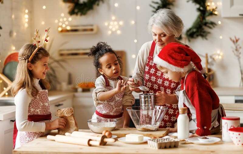 Avó de família multiétnica e três filhos cozinhando biscoitos de natal juntos na cozinha foto de stock