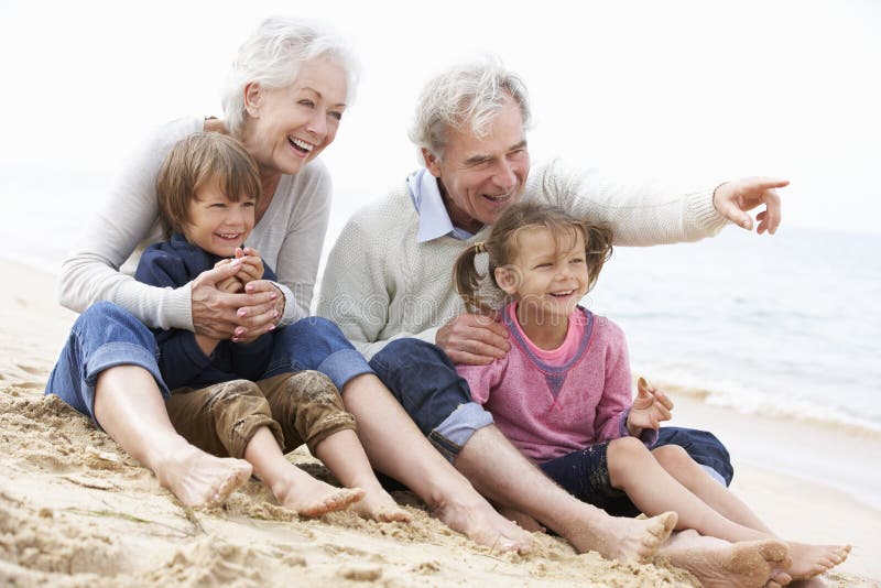 Avós e netos que sentam-se na praia junto