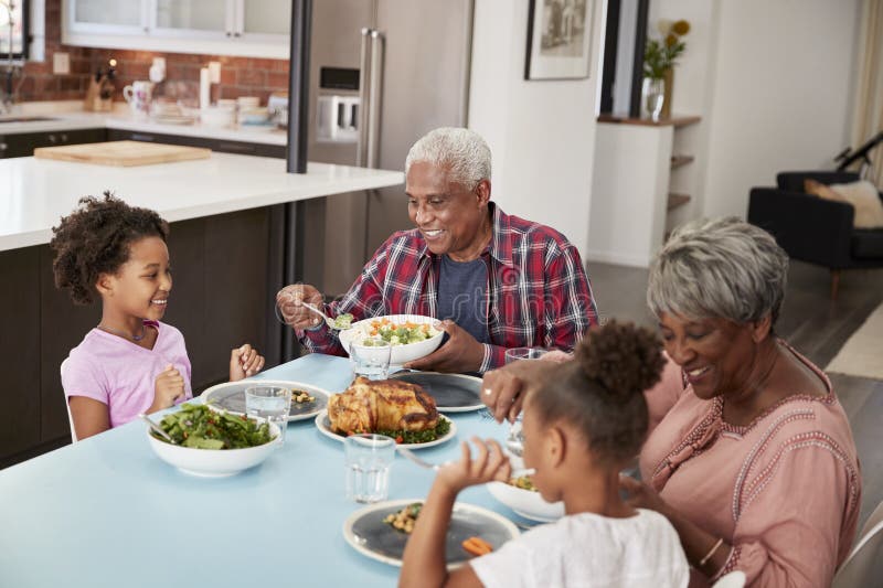 Avós que apreciam a refeição em casa com netas foto de stock Avós que apreciam a refeição em casa com netas foto de stock