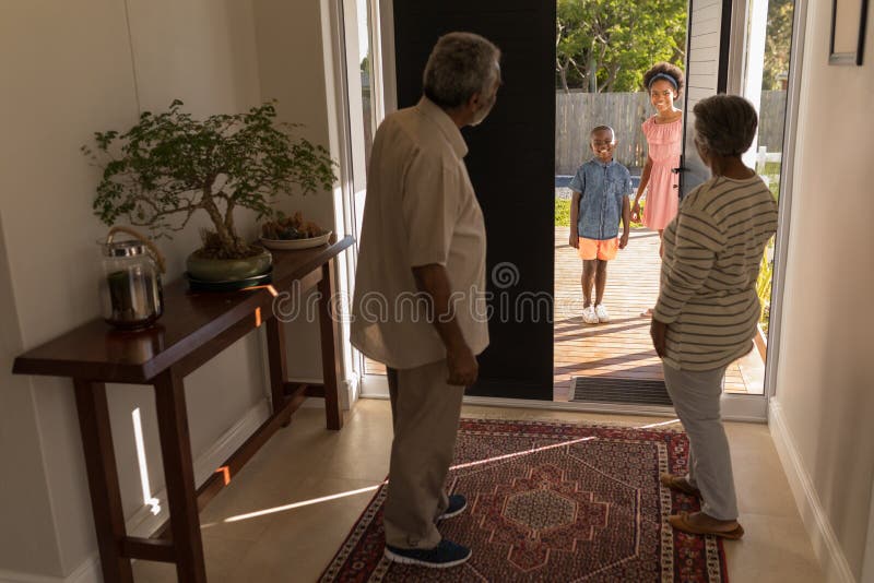 Avós que estão perto da porta e que convidam seus netos na casa imagens de stock royalty free Avós que estão perto da porta e que convidam seus netos na casa imagens de stock royalty free