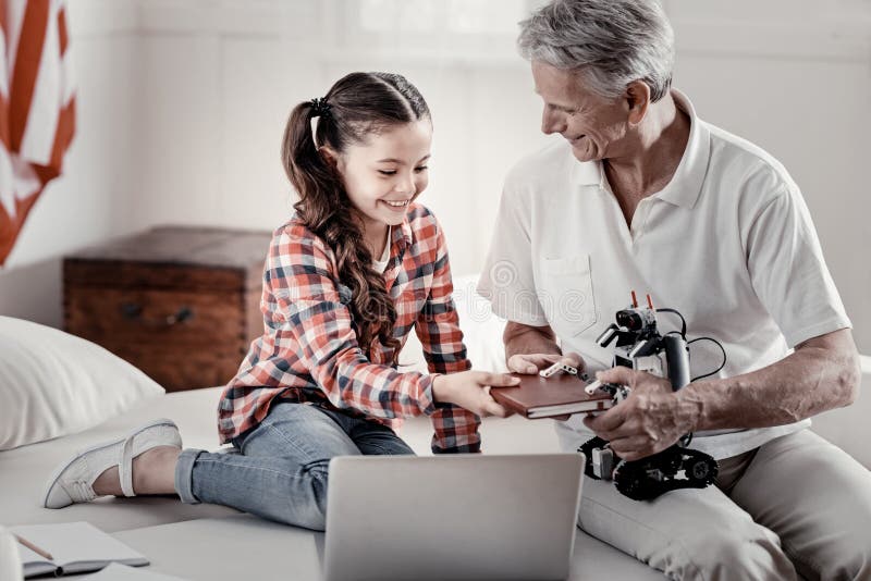 Avô considerável loving e neta pequena que têm o divertimento com robô fotografia de stock Avô considerável loving e neta pequena que têm o divertimento com robô fotografia de stock