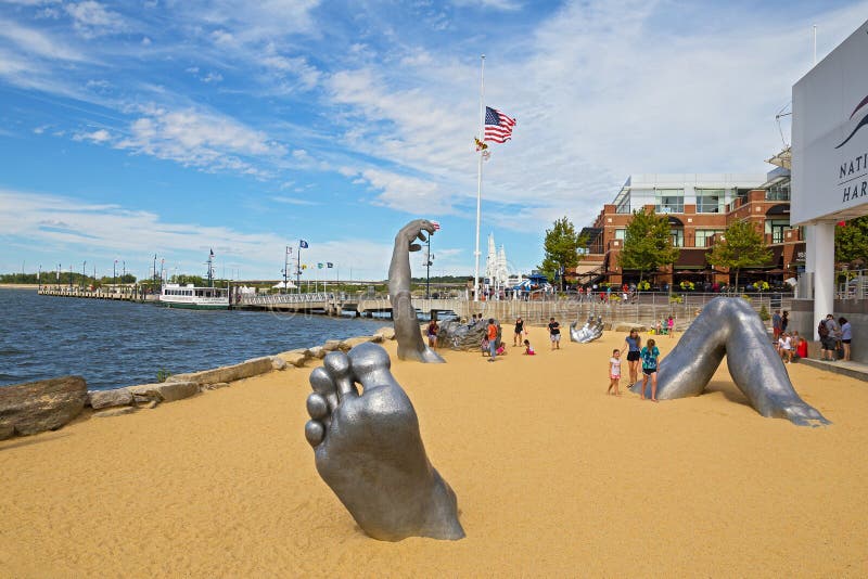OXON HILL, MARYLAND, USA - SEPTEMBER 11, 2016: Awakening Sculpture at National Harbor. A famous statue of a giant embedded in the earth created by J. Seward Johnson Jr. OXON HILL, MARYLAND, USA - SEPTEMBER 11, 2016: Awakening Sculpture at National Harbor. A famous statue of a giant embedded in the earth created by J. Seward Johnson Jr