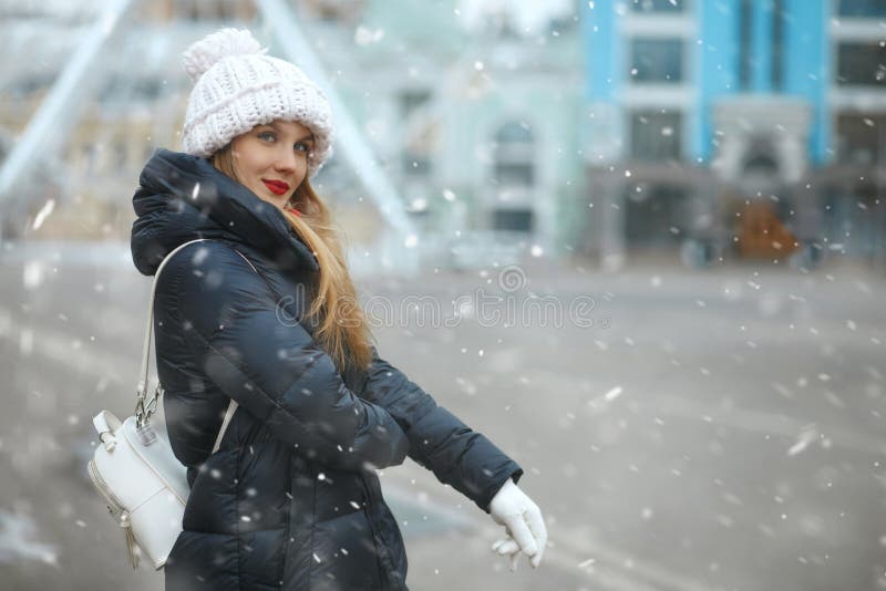 Awesome blond lady walking at the city with snowflakes royalty free stock photography