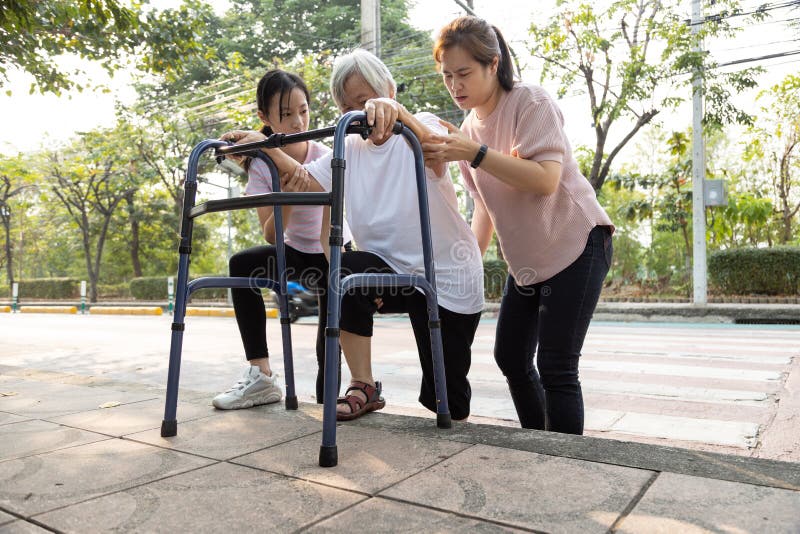 Ayuda a madre asiática y a su hija, cuidado, apoyo a abuela senior al aire libre después de cruzar el camino, barrera del sendero imagen de archivo libre de regalías