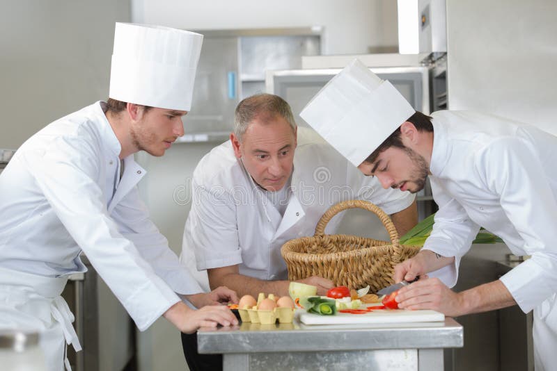 Ayudante de observación del principal cocinero que adorna el plato imagen de archivo Ayudante de observación del principal cocinero que adorna el plato imagen de archivo