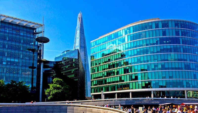 View of City Hall and the Shard in London by the River Thames with business people enjoying the lunch time break in the sunshine. View of City Hall and the Shard in London by the River Thames with business people enjoying the lunch time break in the sunshine.