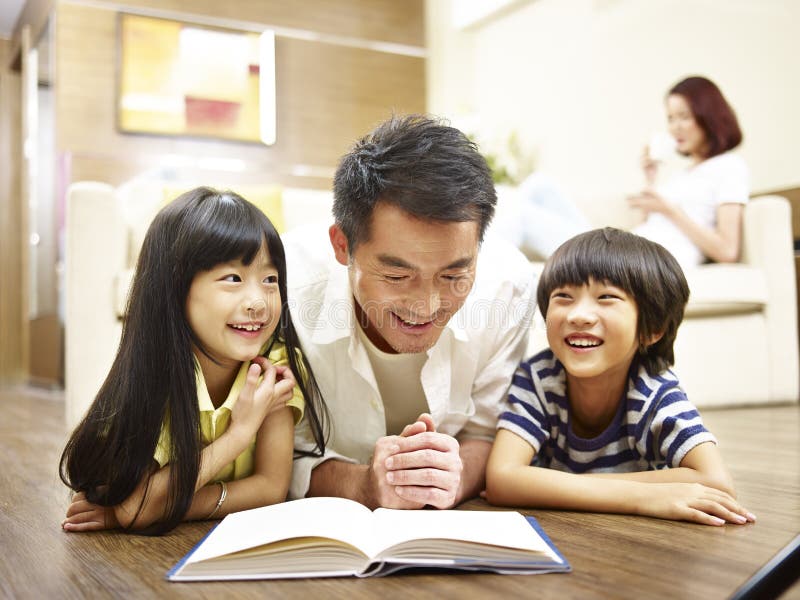 Aziatisch het boek van de vaderlezing het vertellen verhaal aan twee kinderen stock foto's Aziatisch het boek van de vaderlezing het vertellen verhaal aan twee kinderen stock foto's