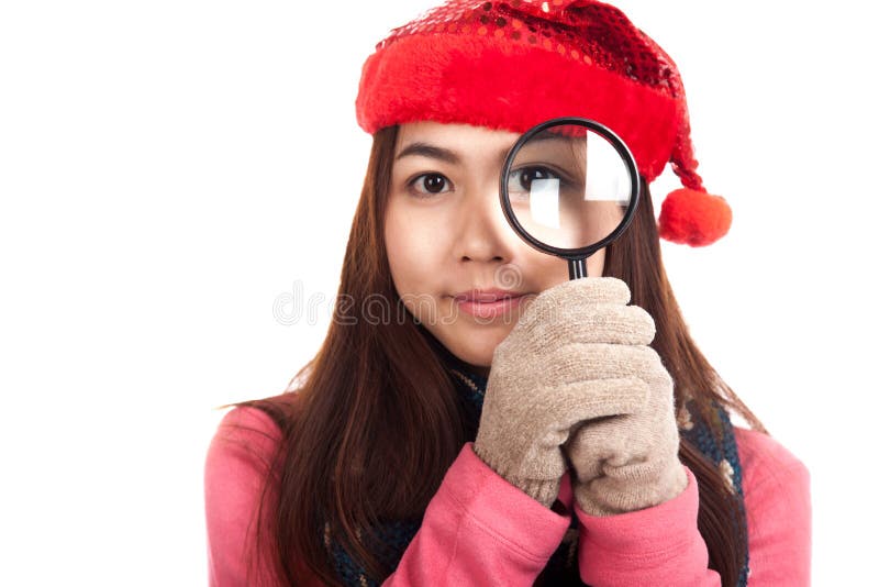 Aziatisch meisje met rood Kerstmishoed en vergrootglas royalty-vrije stock fotografie Aziatisch meisje met rood Kerstmishoed en vergrootglas royalty-vrije stock fotografie