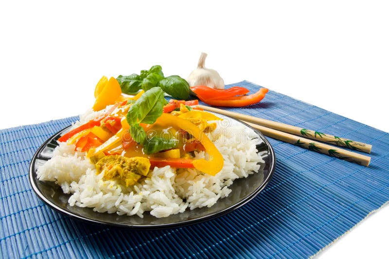 A whole black dish on a blue wooden place met with colorful Asian food. Two chopsticks in the background and fresh ingredients. A whole black dish on a blue wooden place met with colorful Asian food. Two chopsticks in the background and fresh ingredients.