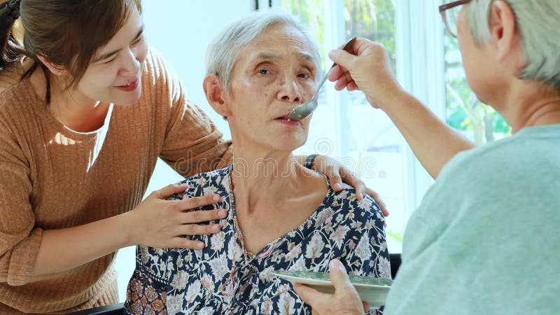 Aziatische dochter, bejaarde vrouw of familievriendelijke vriendin die oudere patiënten of moeder in een rolstoel voedt, moe, ver