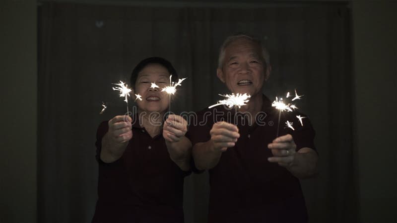 Aziatische hogere paar het spelen sterretjes, brandcracker bij nacht Concept het vieren het leven royalty-vrije stock fotografie Aziatische hogere paar het spelen sterretjes, brandcracker bij nacht Concept het vieren het leven royalty-vrije stock fotografie