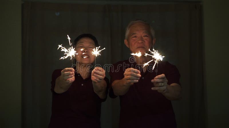 Aziatische hogere paar het spelen sterretjes, brandcracker bij nacht Concept het vieren het leven royalty-vrije stock foto Aziatische hogere paar het spelen sterretjes, brandcracker bij nacht Concept het vieren het leven royalty-vrije stock foto