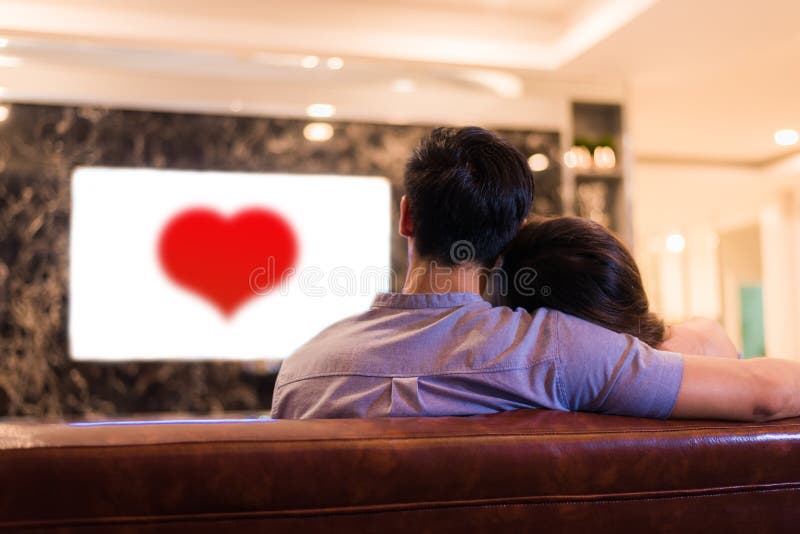 Aziatische jonge minnaars die op televisie op bank letten Paren en Echt royalty-vrije stock afbeeldingen Aziatische jonge minnaars die op televisie op bank letten Paren en Echt royalty-vrije stock afbeeldingen