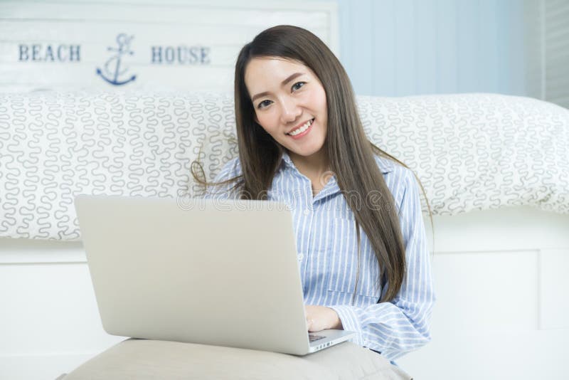Aziatische jonge vrouw die laptop computer in haar slaapkamer met behulp van stock foto Aziatische jonge vrouw die laptop computer in haar slaapkamer met behulp van stock foto